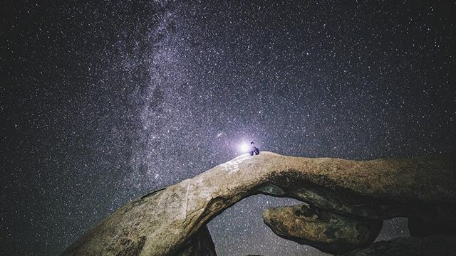 person sitting on rock communicating with stars